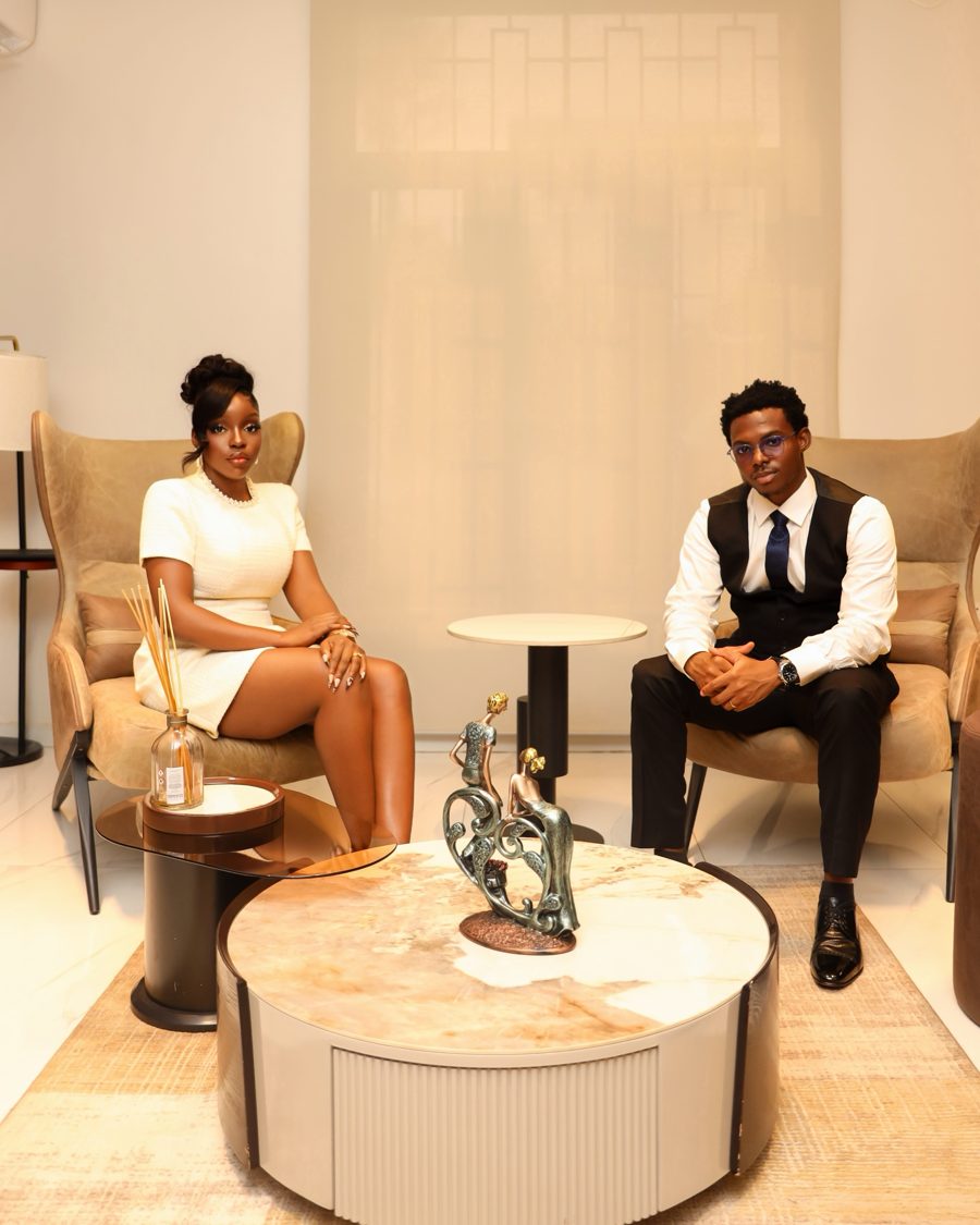 Ogoo and Makuo seated in armchairs either side of a round marble table