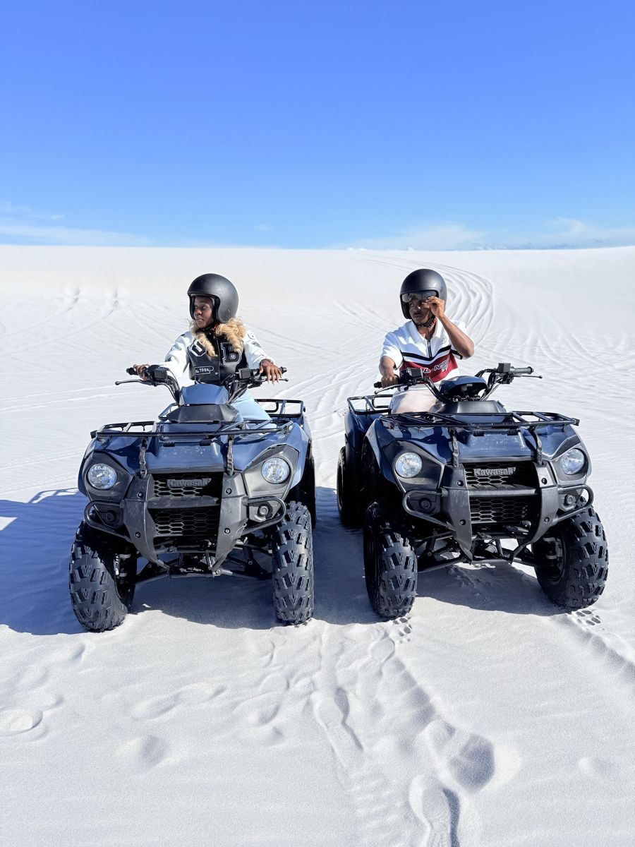 Ogoo and Makuo on quad bikes on white sand dunes